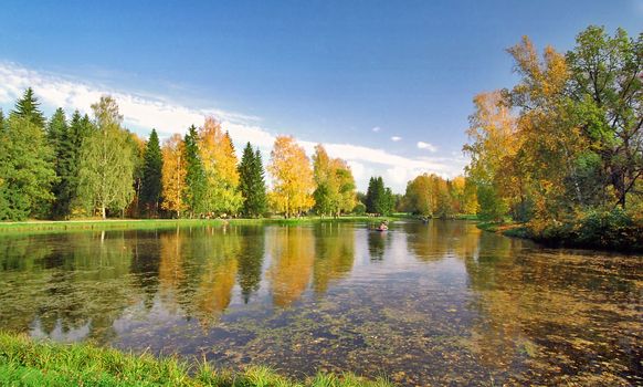 Autumn pond with boats and reflections