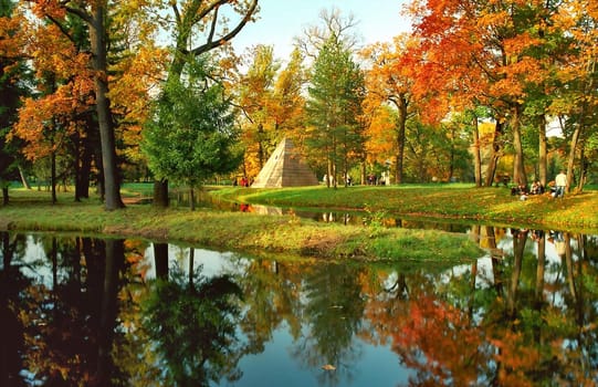 Autumn trees and pyramid in the park near water