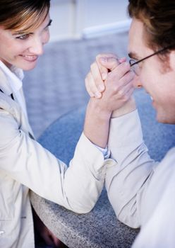close view of man and woman sitting looking at each other and arm wrestling