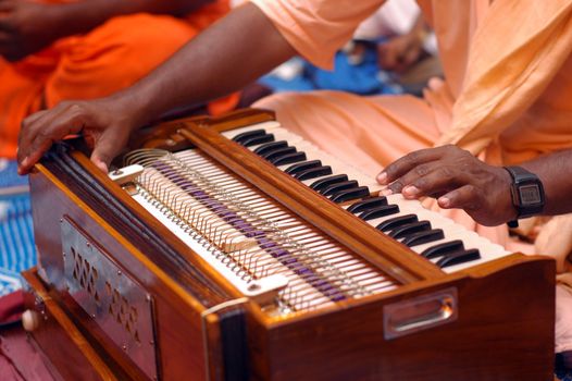 Hare Krishna devotee playing harmonium during music chanting festival.