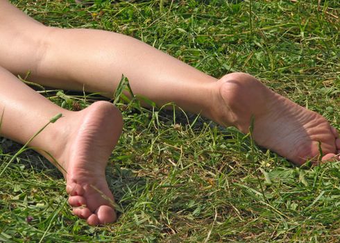 Woman's legs on the grass in a sunny day