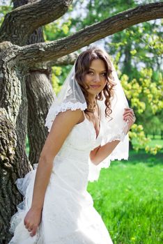 Attractive Bride stands about trees in the park