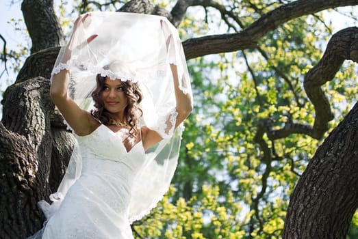 Attractive Bride stands about trees in the park