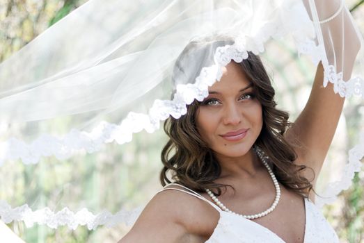 Young cute bride posing with a veil