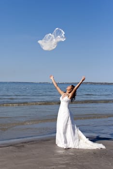 beautiful young bride throwing the veil near the sea