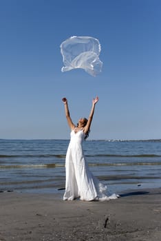 beautiful young bride throwing the veil near the sea