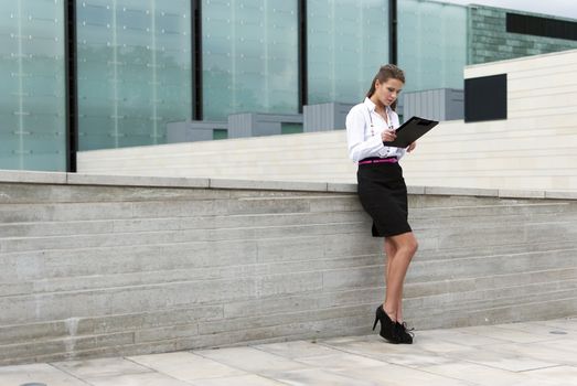 business woman in black skirt sign documents on the background of a business building