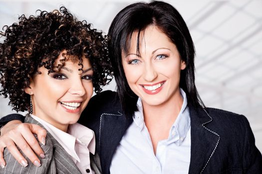 Two beautiful happy women hugging, looking at camera