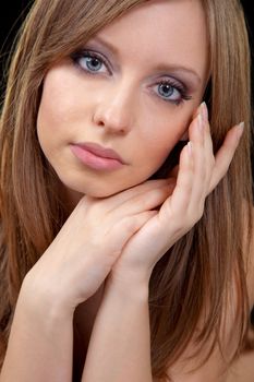 Close-up of beautiful female face, hands under chin, looking at camera