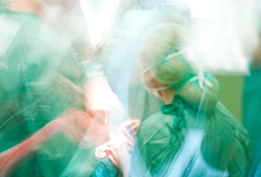 Blurred figures of people with medical uniforms and masks during surgery