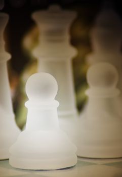Macro shot of glass chess pawn
 against a dark background 