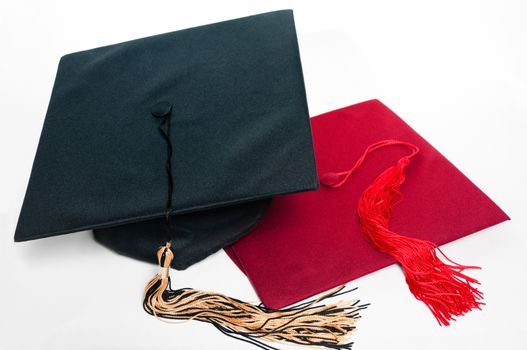 Black and red graduation caps with tassels on the white background.