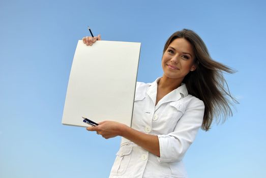 beautiful girl in a white jacket holding blank paper. sea on the background