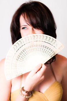 sexy image of beautiful young brunette model holding a white with Chinese hand fan in front of her face