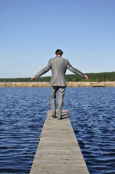 man in a gray suit walking on the pier, from the back