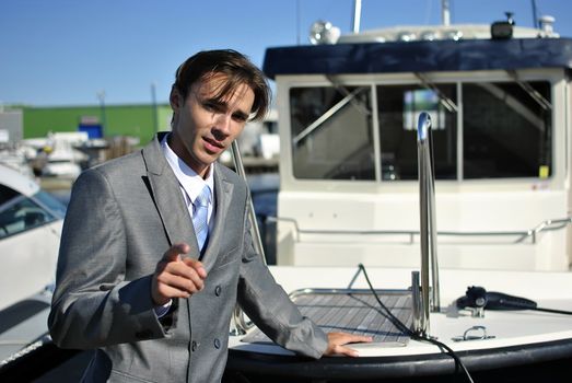 man in a gray business suit says something near the yacht