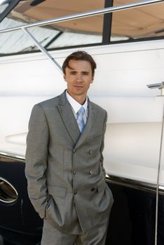 man in a gray business suit near the yacht