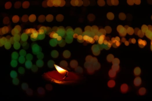 A festive candle lit on the occassion of Diwali/Christmas in India, on the backdrop of colorful blur lights.