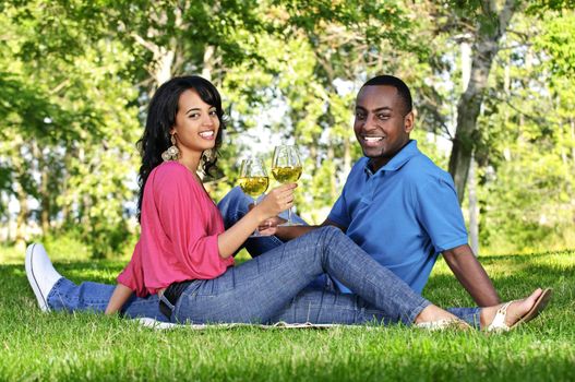 Young romantic couple celebrating with wine in summer park