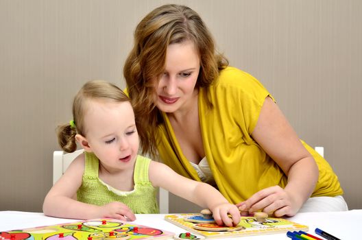 little girl and mom playing in a children puzzle