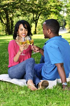 Young romantic couple celebrating with wine in summer park