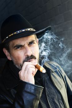 Man with beard in cowboy hat smoking cigar