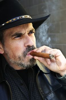 Man with beard in cowboy hat smoking cigar