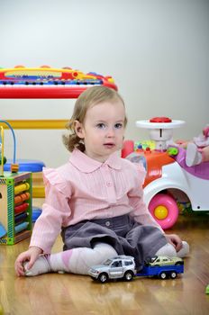 little girl in a room with toys, playing with cars