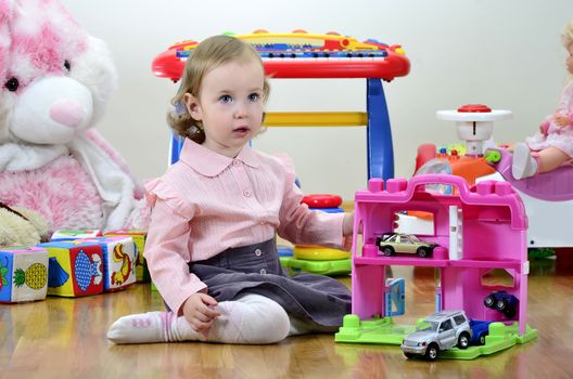 little girl in a room with toys, playing with cars