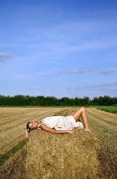 girl in a rural clothing lying on the haystack. space for text