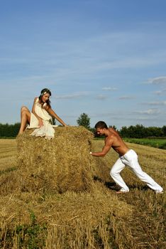 bodybuilder pushes a haystack with a girl on top, space for text