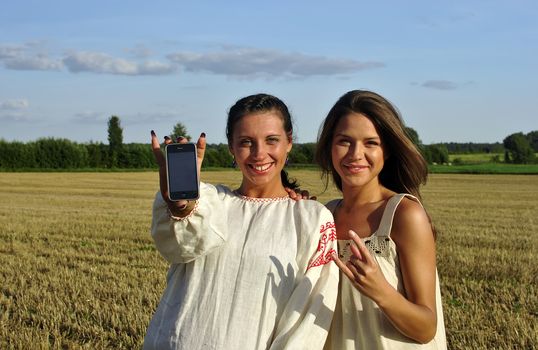 Two girls in a rural clothing show mobile phone into camera