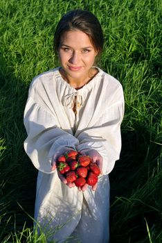 girl in a linen shirt, holding a strawberry in hand. focus on berries