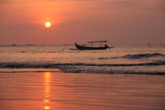 Drifting boat on a sunset. Coast of the Indian ocean. Bali
