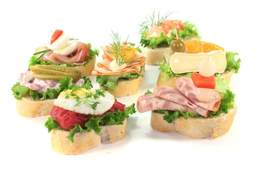 Canape with lettuce, cheese, sausage and eggs on a white background