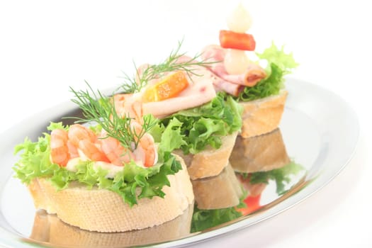 Canape with lettuce, shrimps, sausage and vegetables on a white background