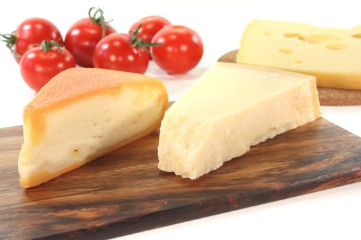 a selection of cheeses with tomato on a wooden board