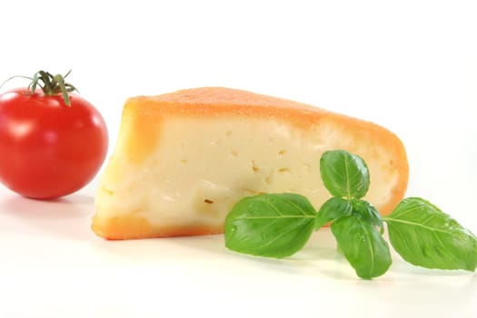 a piece of soft cheese with tomato and basil on a white background