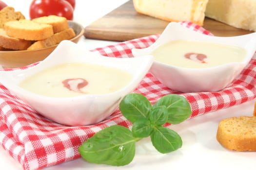 Cheese cream soup with tomato, bruschetta and basil on a white background