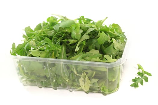 a bowl of rocket leaves on a white background