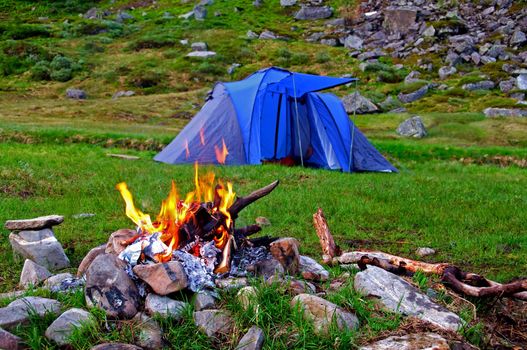 Camping tent and bonfire in the mountains