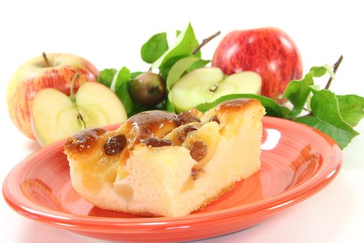 a piece of apple cake with apples and leaves on a white background