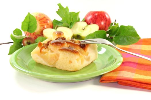 a piece of apple cake with apples and leaves on a white background