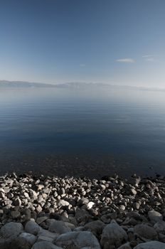 Rocky shore and mountain background at blue lake