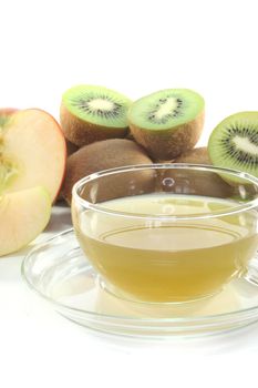 a glass of Kiwi and apple tea with fresh kiwis and apples