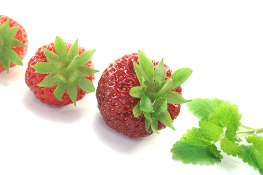 fresh red strawberries with lemon balm on a white background