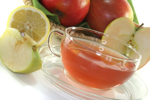 a glass of apple-lemon tea with fresh apple and lemon