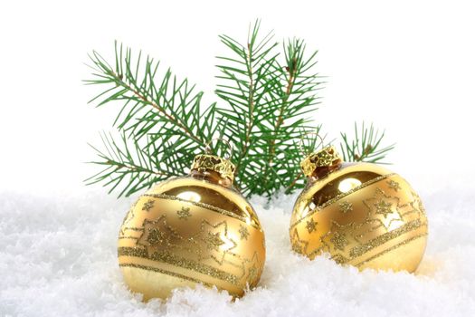 one golden Christmas ball with pine branches lies in the snow