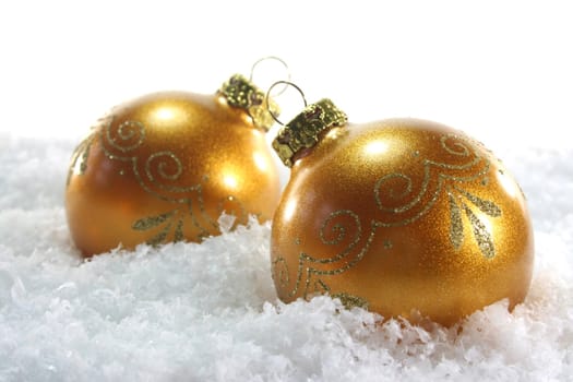 two golden Christmas balls lying in the snow