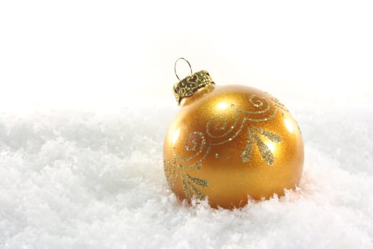 one golden Christmas ball lies in the snow